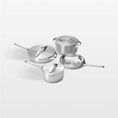 three pots and two pans on a white surface