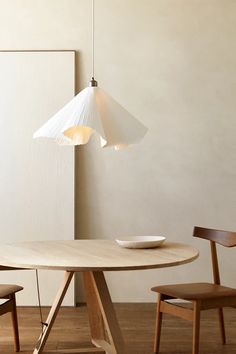 a wooden table with two chairs and a light hanging from it's ceiling fixture