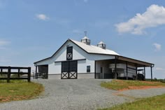 a large white barn sitting on top of a lush green field