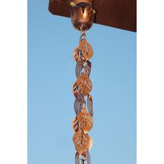 a metal wind chime hanging from the side of a wooden structure in front of a blue sky