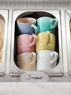 four different colored coffee mugs in a metal container