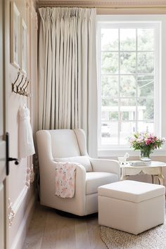 a white chair and ottoman in front of a window