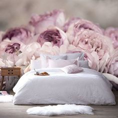 a bed sitting next to a bunch of pink flowers