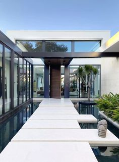 the entrance to a modern home with large windows and water features in the pool area