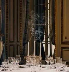 the table is set with wine glasses, candles and smokestacks in front of an ornate mirror