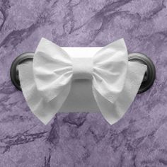 a toilet paper roll with a white bow on it's end in front of a purple marble wall