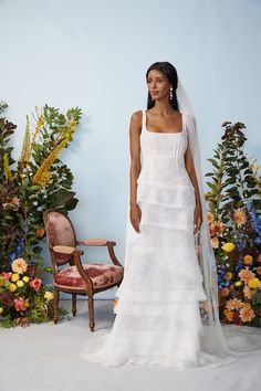 a woman standing in front of flowers wearing a wedding dress