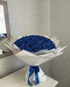 a bouquet of blue roses sitting on top of a white table next to a mirror