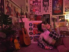 a woman sitting on the floor taking a selfie with her cell phone in front of some guitars