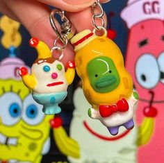 a person holding two cartoon key chains in their hand