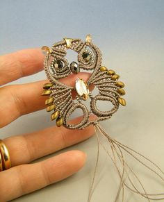 an owl brooch sitting on top of someone's hand