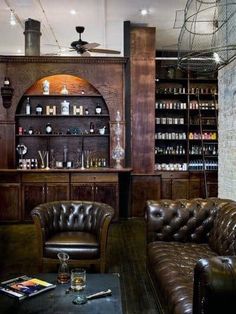 a room with leather couches and shelves full of bottles