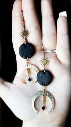 a person is holding some kind of earrings in their hand with the sun and moon on it