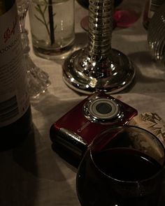 a table topped with wine glasses and a camera next to a bottle of wine on top of a table