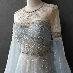 a dress with beading on the shoulders and long sleeves is displayed in front of a mannequin's head