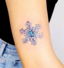 a snowflake tattoo on the wrist is shown in blue and pink colors,