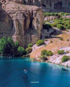 people are boating in the water near some cliffs