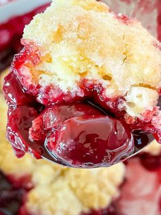 a close up of a spoon with some food on it and berries in the background