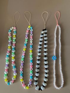 three necklaces are lined up next to each other on a table, one is decorated with beads and the other has an evil eye