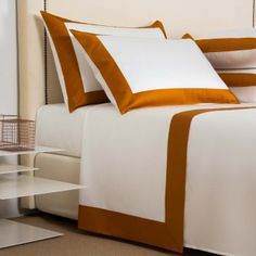 a bed with white and brown sheets and pillows