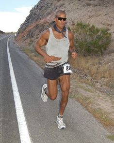 a man running down the road with sunglasses on his head and an armband around his waist