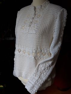 a white crocheted sweater on a mannequin