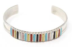 "Very attractive multi-color inlay bracelet featuring coral, turquoise, mother of pearl, jet pink mussel shell and gold lip by Zuni artist Lucy Shekya.. This bracelet will comfortably fit a wrist with a circumference of up to 6.75"" and weighs approximately 16.7 grams. Handcrafted by Zuni Artist Lucy Shekya Size: 3/8"" Wide, 5 1/2"" Tip to Tip (Fits a wrist of up to 6.75"" in circumference) 14.0 cm Tip to Tip (Fits a wrist of up to 17.0 cm in circumference) " Mussel Shell, Gold Lips, Stone Inlay, Coral Turquoise, Multi Stone, Mother Of Pearl, Multi Color, Shells, Coral