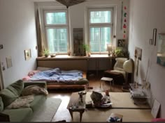 a living room filled with furniture next to two windows and a bed in the corner