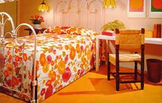 an orange and white bed in a bedroom next to a table with flowers on it