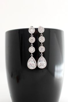 a pair of diamond earrings sitting on top of a black cup