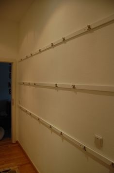 a hallway with white walls and wood flooring next to an open door at night