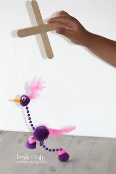 a person holding a wooden cross with a purple bird on it and beaded beads