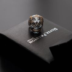 This ring's design is a solid ounce of 925 sterling silver. The ornate craftsmanship features brass details and sugar skulls within the eyes. Catch this Calavera Sugar Skull on sale for only $79.99! ☠️💀    #skullrings #sugarskull #coolskulljewelry #uniqueskulljewery #detailedring #detailedsugarskull #bikerjewelry #ringsforbikers #jewelrygram #sterlingsilver Luxury Skull Ring As Gift, Engraved Metal Skull Ring As A Gift, Collectible Engraved Skull-shaped Rings, Halloween Engraved Skull Ring Gift, Luxury Engraved Skull Jewelry, Engraved Skull Ring For Anniversary, Sugar Skull Ring, Japanese Tattoos, Biker Jewelry