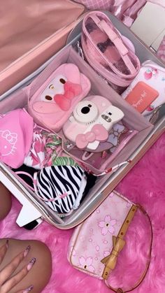 an open suitcase filled with lots of items on top of a pink rug next to a handbag