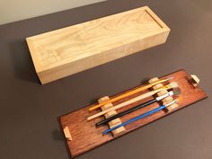 a wooden box with chopsticks in it next to a set of chopsticks