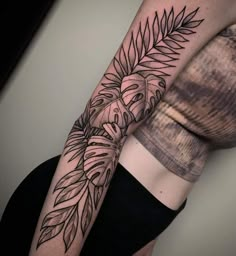 a woman's arm with a black and white tattoo design on the left forearm