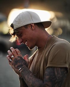 a young man with tattoos on his arm and hand is smiling while holding something in his other hand