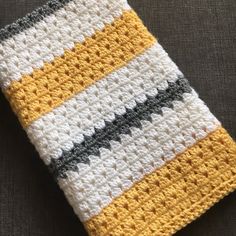 a crocheted yellow and white dishcloth on a gray surface with a black stripe