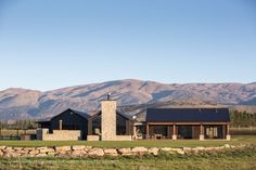 a house in the middle of a field with mountains in the backgrouds