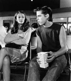 a man and woman sitting next to each other in front of a movie theater screen