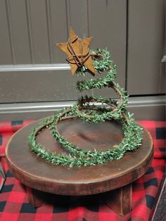 a christmas tree made out of branches on top of a wooden table with red and black checkered cloth