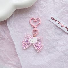 a hello kitty keychain with a pink bow and angel wings on it next to a tag that says good things have come