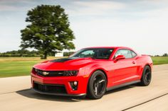 a red chevrolet camaro driving down the road