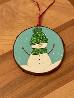 a wooden ornament with a snowman on it's face and green hat