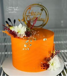 an orange birthday cake with white flowers on top