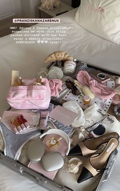 an open suitcase filled with personal items on a bed