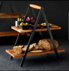 two tiered trays with bread and candles on them in front of a black background