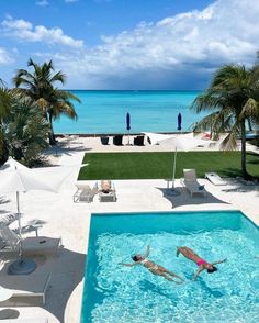 two people swimming in a pool next to the ocean