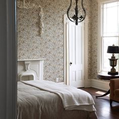 a bedroom with a bed, chair and lamp next to a window in the room