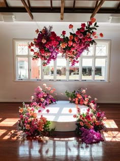 a white table topped with lots of pink and orange flowers on top of a hard wood floor